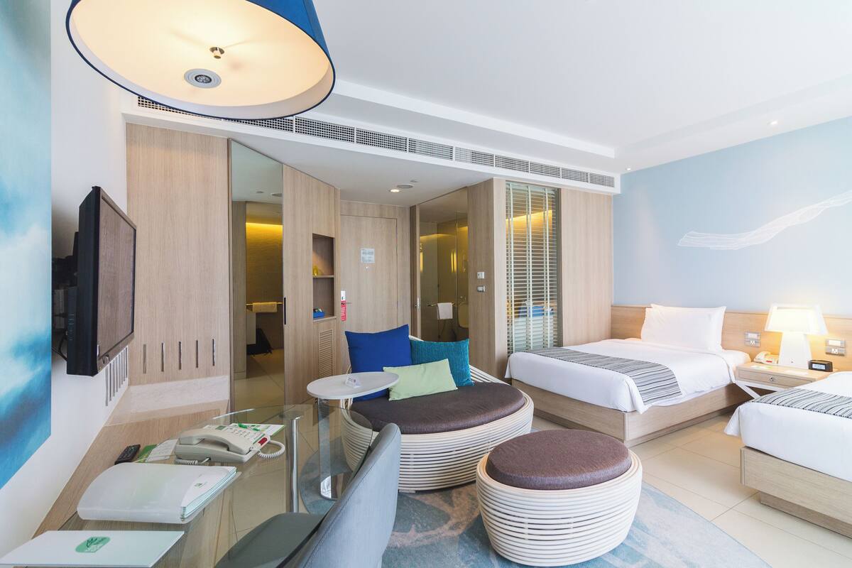 A hotel room with two beds, a sofa, a small table, a telephone, and a lamp.