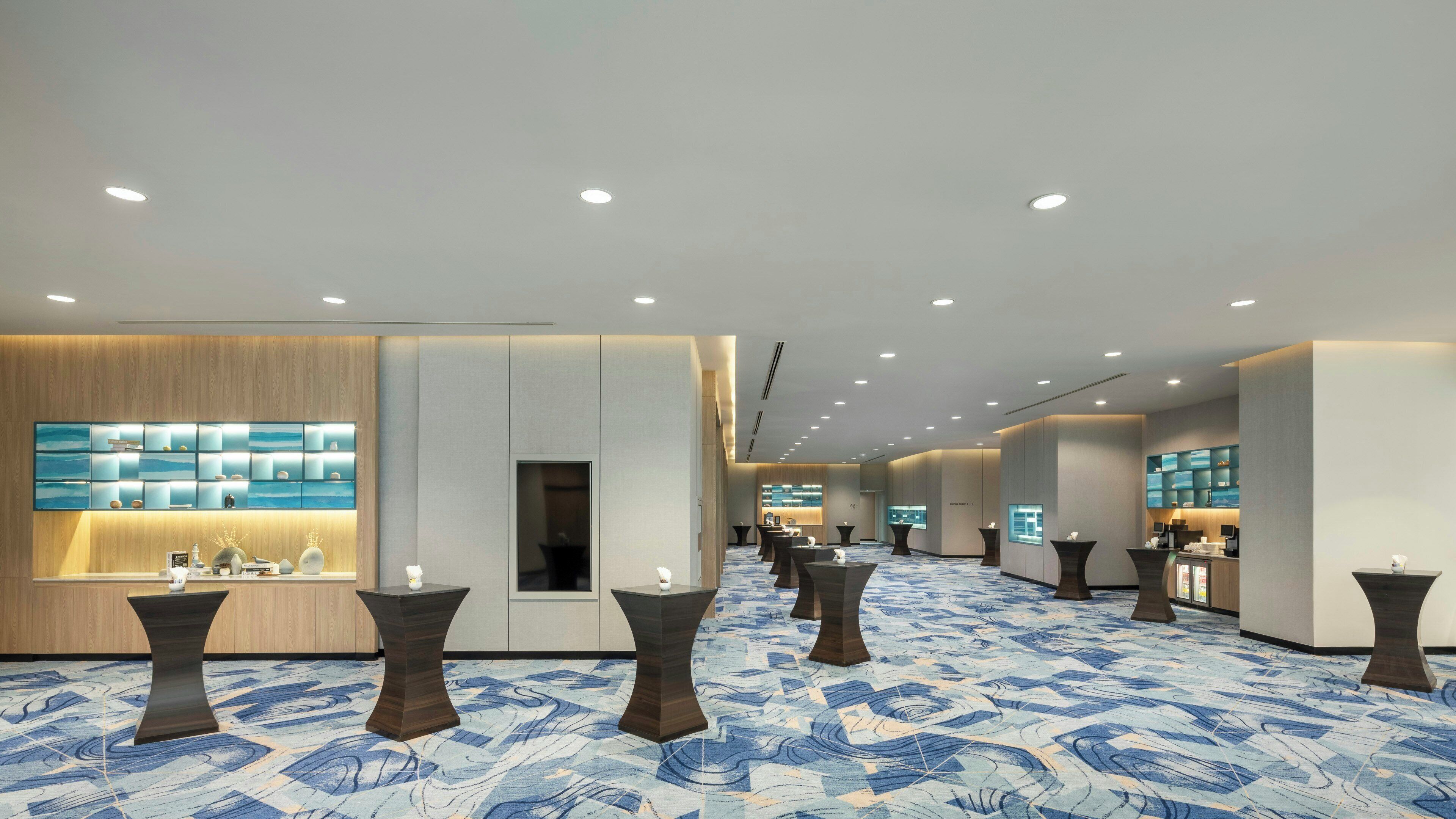 Vestíbulo de hotel con mostrador de recepción, zonas de estar y alfombra estampada.