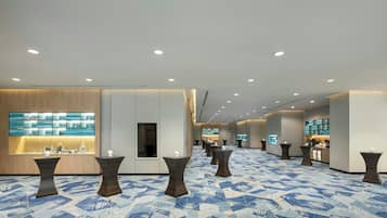Vestíbulo de hotel con mostrador de recepción, zonas de estar y alfombra estampada.