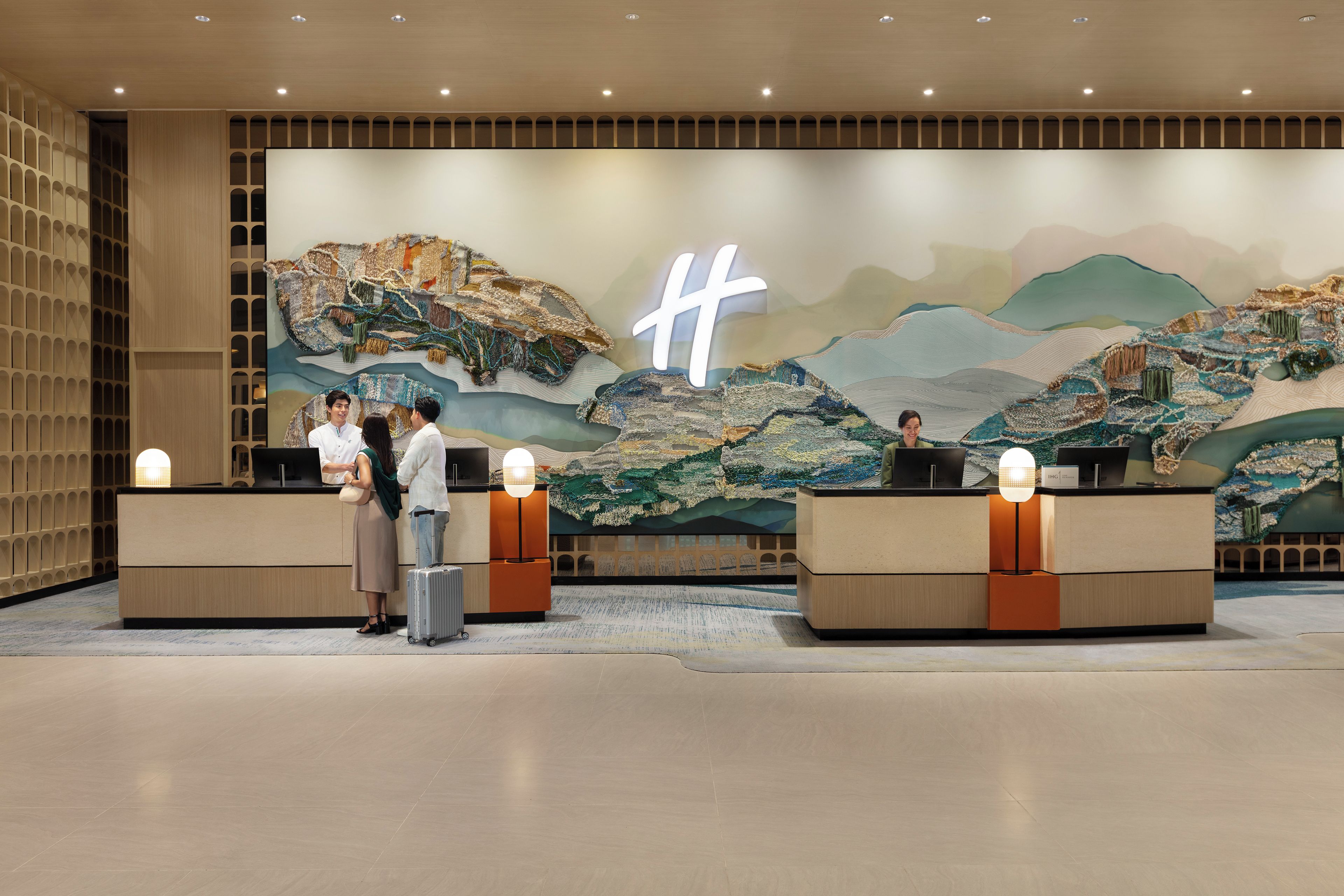 Un espace d’accueil agrémenté d’une grande fresque murale, de deux comptoirs d’accueil et d’un aménagement intérieur moderne.
