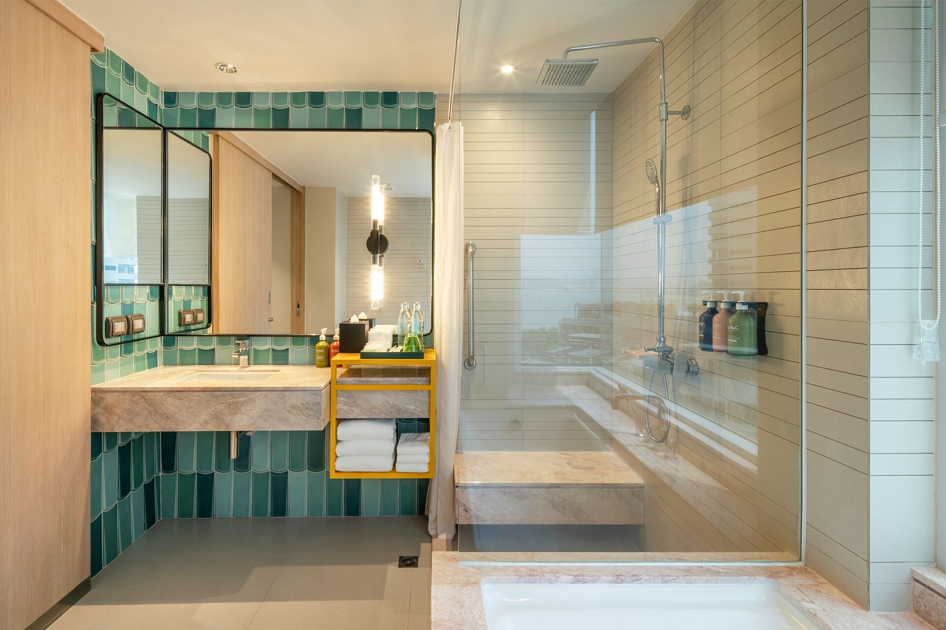 A modern bathroom with a large mirror, a vanity with toiletries, a glass-enclosed shower, and a separate bathtub.