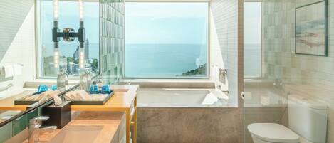 A modern bathroom with a large window, a bathtub, and a toilet.