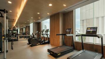 Un gimnasio con cintas de correr, bicicletas estáticas y máquinas de pesas.