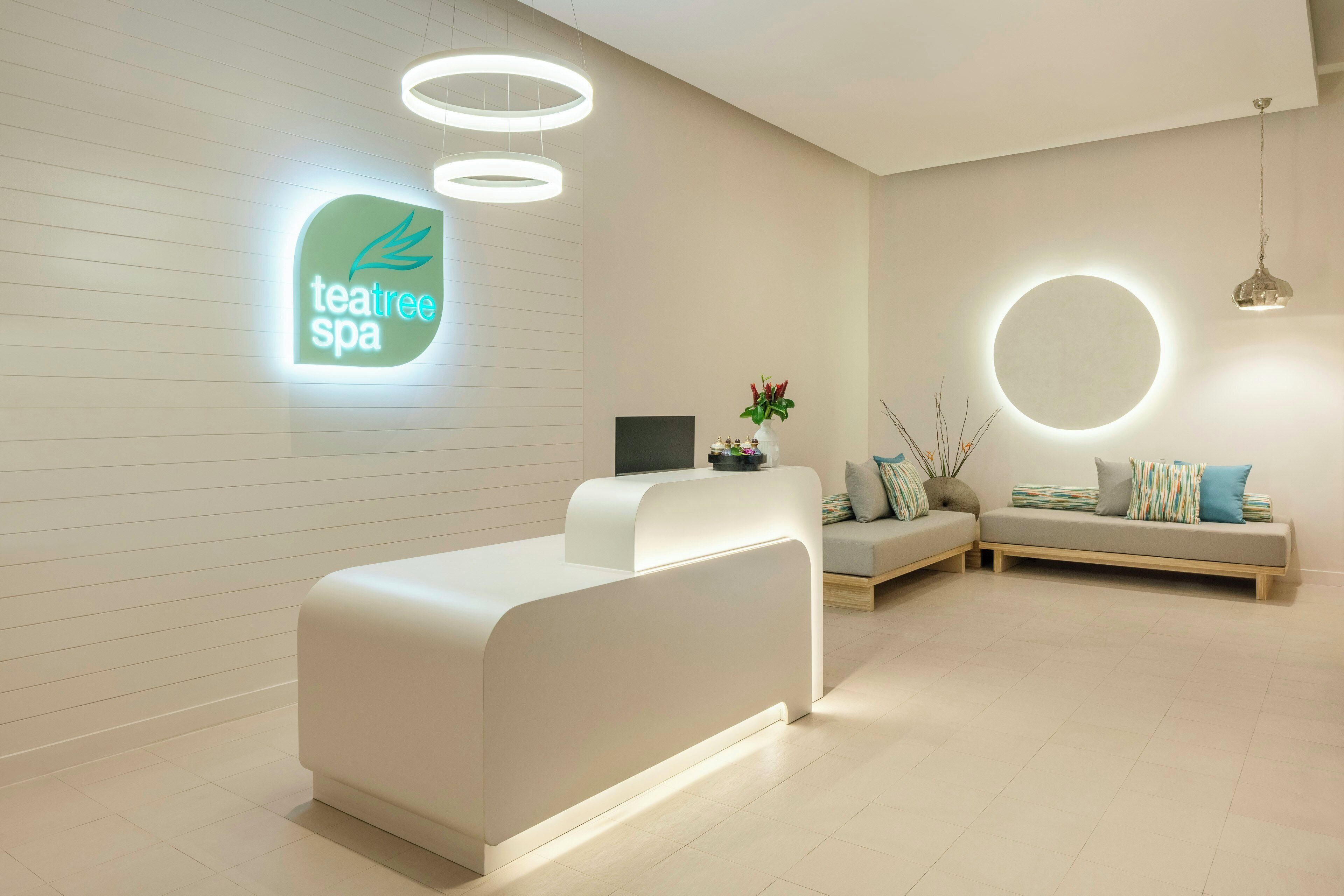 A spa reception area with a modern design, including a reception desk, seating area, and a wall-mounted sign.