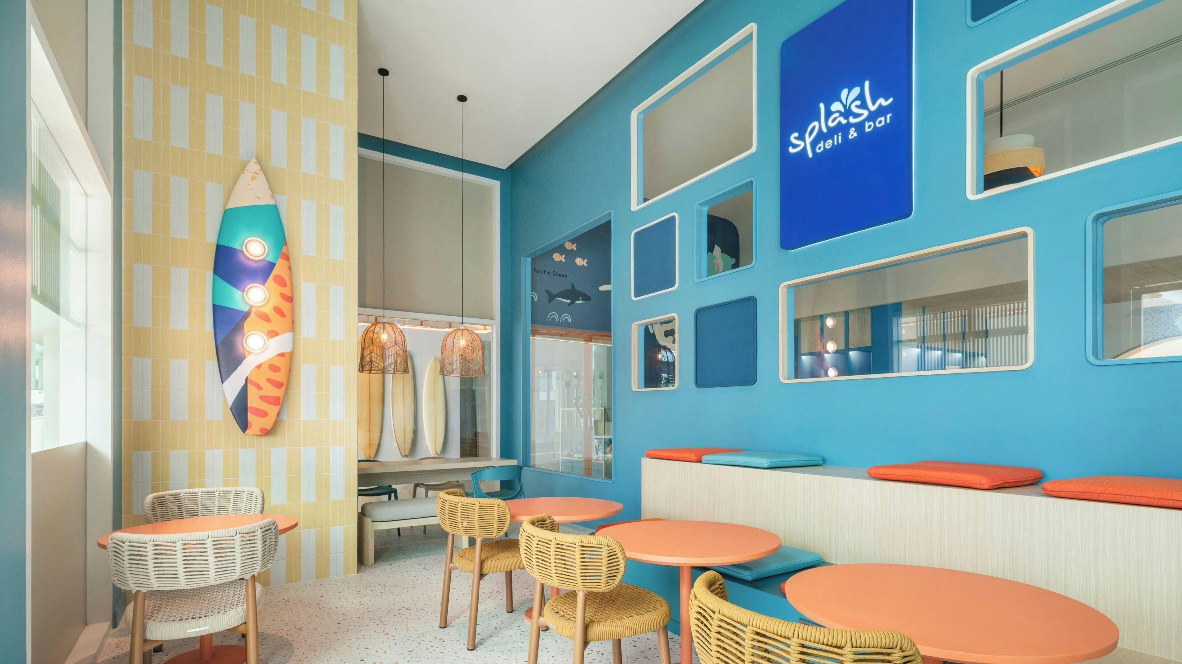 A restaurant interior with blue walls, orange and white furniture, and surfboards displayed on the wall.