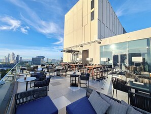 A rooftop terrace with outdoor seating, a city skyline view, and a modern building structure. - Holiday Inn Pattaya by IHG (Pattaya)