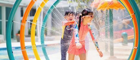 Two children playing in a water play area with colorful rings.