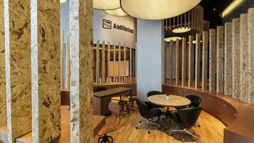 An auditorium with a modern design, featuring a wooden wall, a round table, and black chairs.