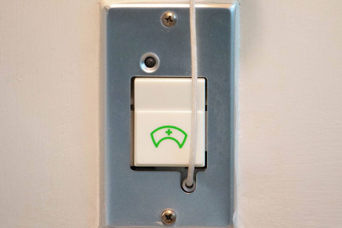 A light switch with a green telephone icon and a red hanging ornament.