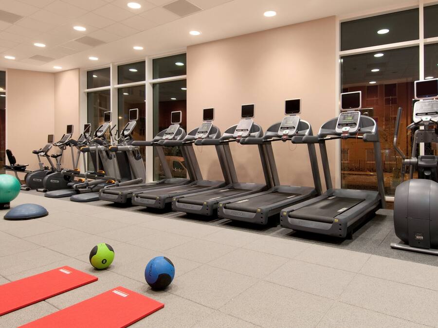 A gym with treadmills, exercise balls, and red mats.