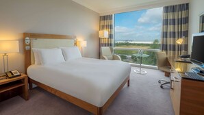Habitación de hotel con cama, escritorio, silla y vistas al exterior.