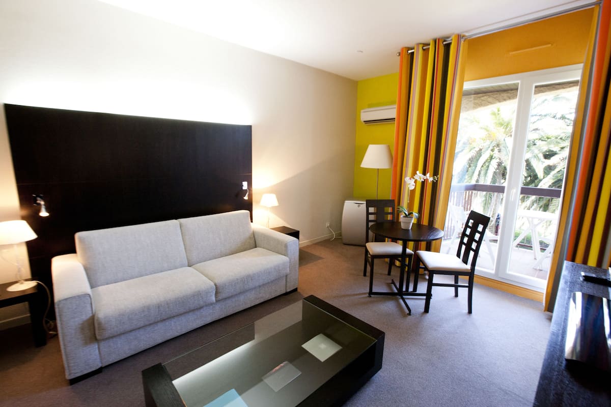 Uma sala de estar moderna com sofá, mesa de centro de vidro e um espaço de jantar com cadeiras e mesa.