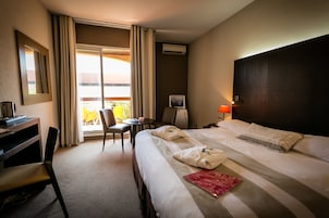 Ein Hotelzimmer mit Bett, Schreibtisch, Stuhl und Blick ins Freie.