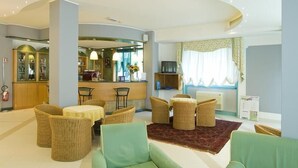 Un hall de hotel con muebles de mimbre, una zona de bar y vistas al exterior.