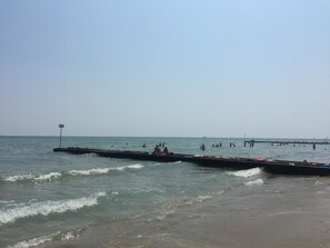 A beach with boats and people in the water.