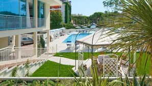 Un hotel moderno con piscina en la azotea, mobiliario exterior y exuberante jardinería.