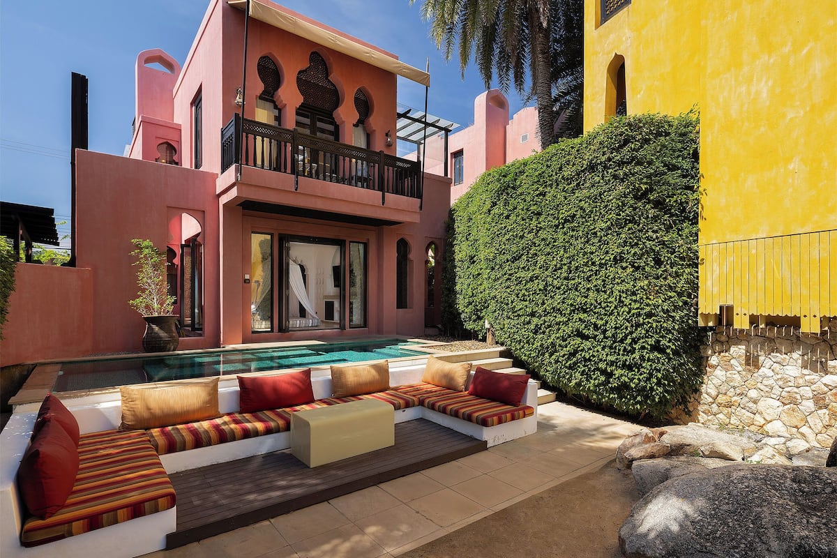 A two-story building with a pool, outdoor seating, and a well-maintained garden.