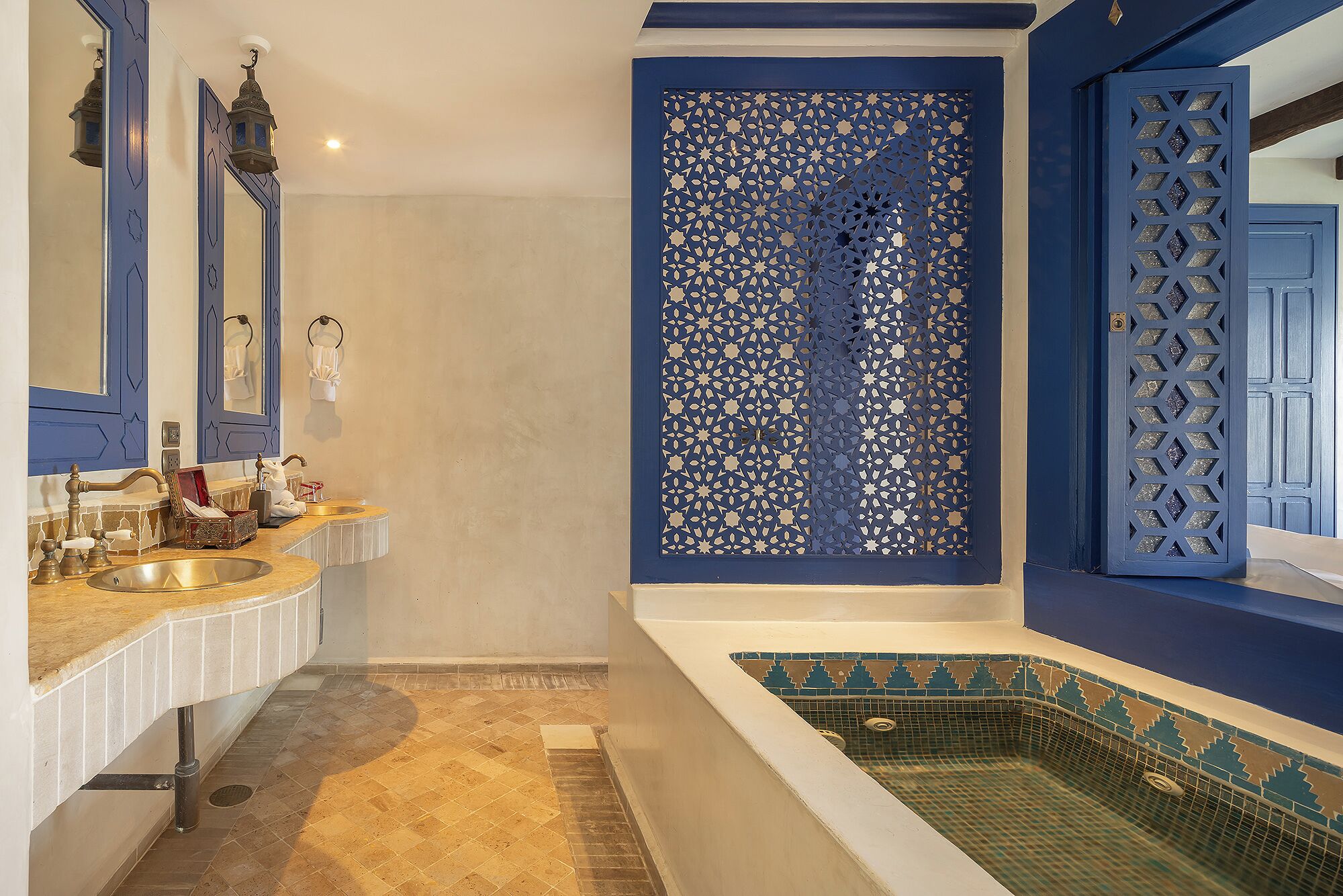Een badkamer met een badkuip, een wastafel en een decoratieve blauwe scheidingswand.