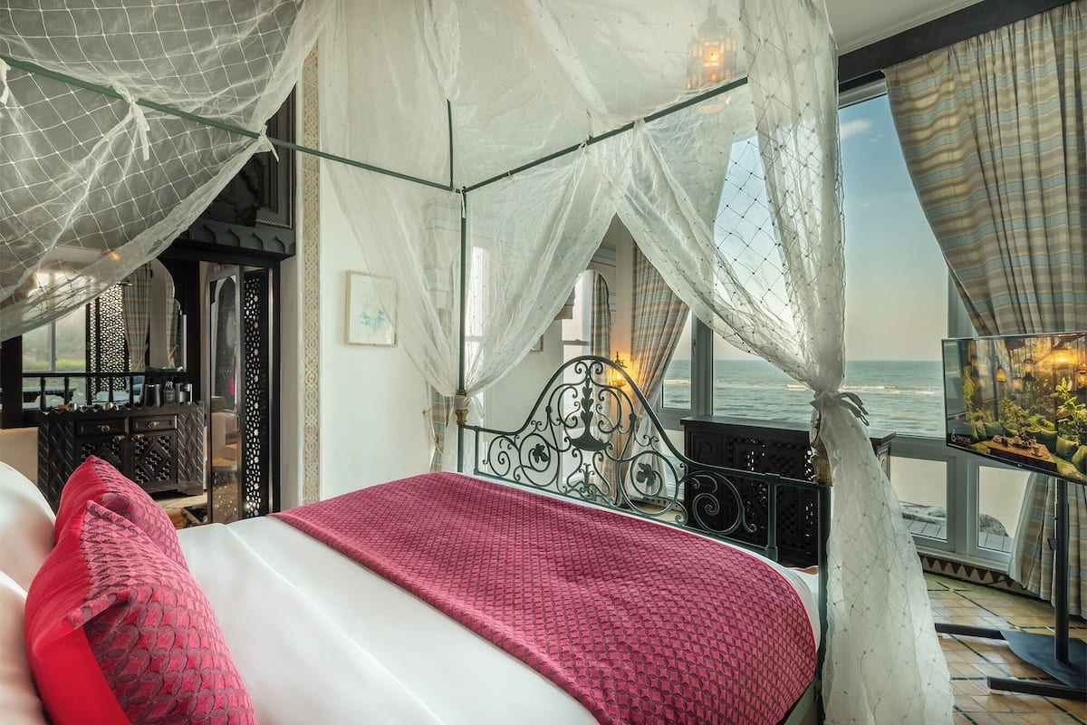 A bedroom with a bed, a balcony, and a view of the sea.