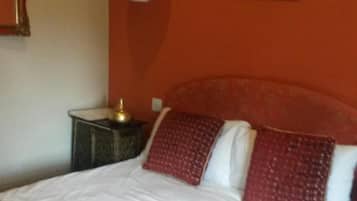 Ein Hotelzimmer mit einem großen Bett, einem Nachttisch, einer Lampe und einem gerahmten Bild an der Wand.
