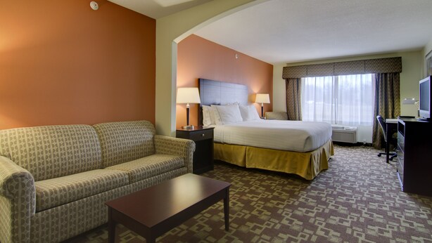 Ein Hotelzimmer mit Bett, Sofa, Schreibtisch und Fernseher.