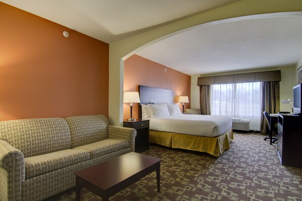 A hotel room with a bed, a sofa, a desk, and a television. - Holiday Inn Express Hotel & Stes Kansas City Sports Complex by IHG (Kansas City)