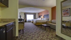 Ein Hotelzimmer mit Bett, Schreibtisch, Stuhl, Sofa und einer Küchenzeile.