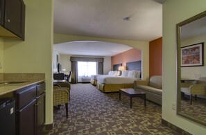 A hotel room with a bed, a desk, a chair, a sofa, and a kitchenette. - Holiday Inn Express Hotel & Stes Kansas City Sports Complex by IHG (Kansas City)