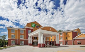 Um hotel Holiday Inn Express & Suites com entrada coberta e várias janelas.