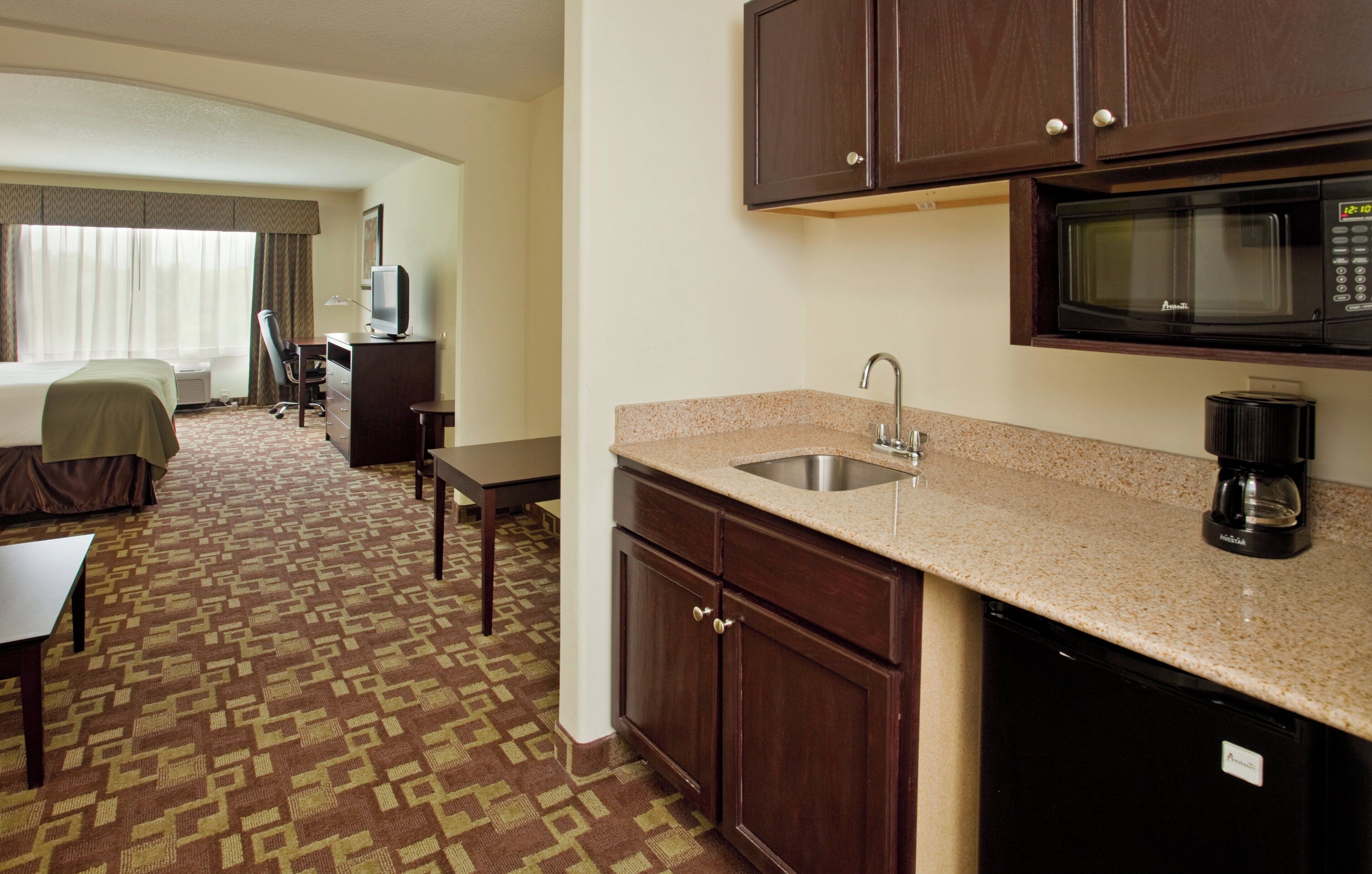 Une chambre d’hôtel équipée d’une kitchenette, d’un lit, d’un bureau et d’une chaise.