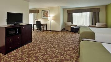 A hotel room with a bed, a desk, a chair, a television, and a lamp.