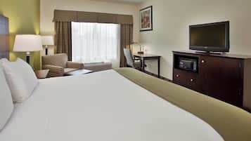 A hotel room with a large bed, a desk with a chair, a television, and a window with curtains.