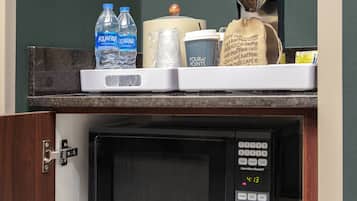 A kitchen area with a microwave, a coffee machine, and a water dispenser on the counter.