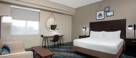 Una habitación de hotel con cama, escritorio, silla y sofá.