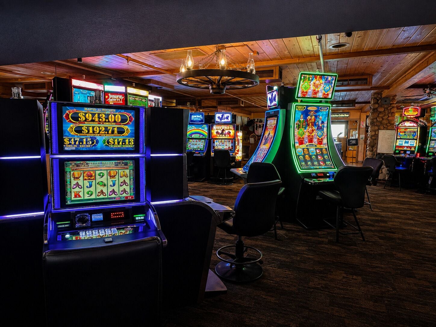 A casino with multiple slot machines and a wooden ceiling.