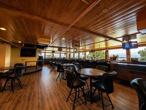A restaurant with wooden ceiling and walls, multiple seating areas, and a view of the outdoors. - Topaz Lodge (Gardnerville)