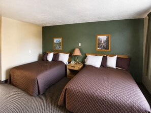A hotel room with two beds, a nightstand with a lamp, and two framed pictures on the wall. - Topaz Lodge (Gardnerville)