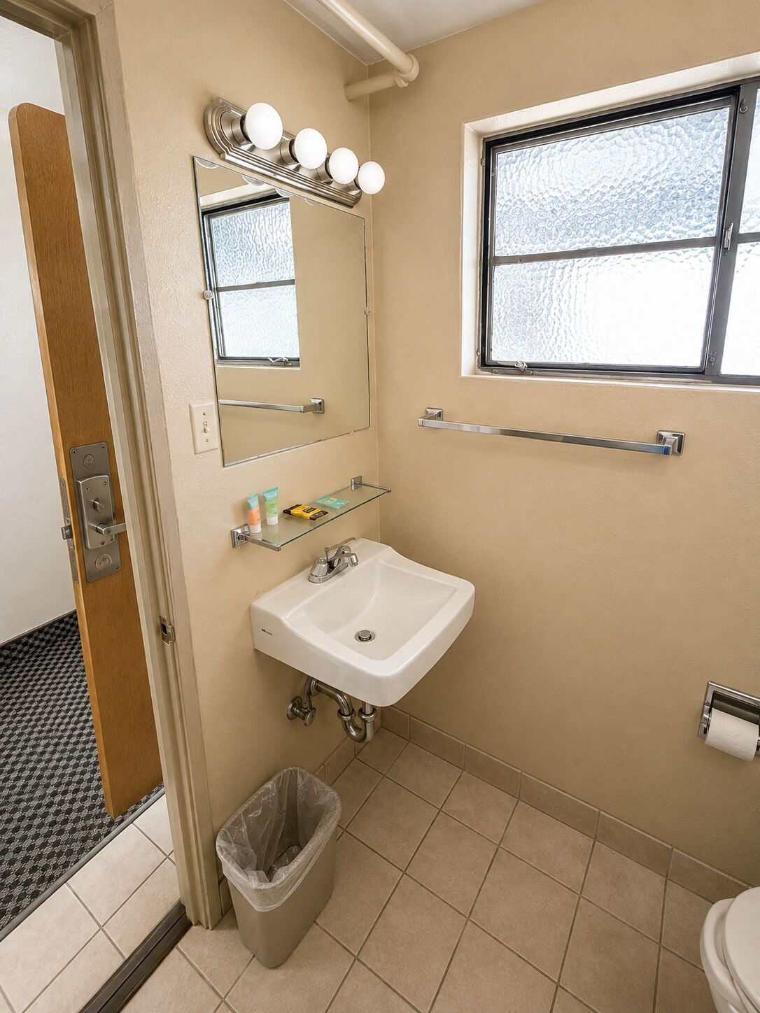 Une salle de bain avec un lavabo, un miroir, des luminaires et une fenêtre.