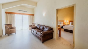 A hotel room with a brown leather sofa, a wooden chair, a bed with two pillows, and a nightstand with a lamp. - Comfort Inn Puerto Vallarta Golfside & Marina (Puerto Vallarta)