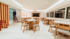 A modern dining area with wooden tables and chairs, a large window, and a view of the outside. - Comfort Inn Puerto Vallarta Golfside & Marina (Puerto Vallarta)