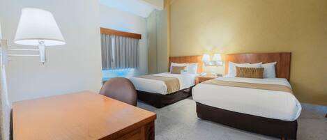 A hotel room with two beds, a desk, and a chair.