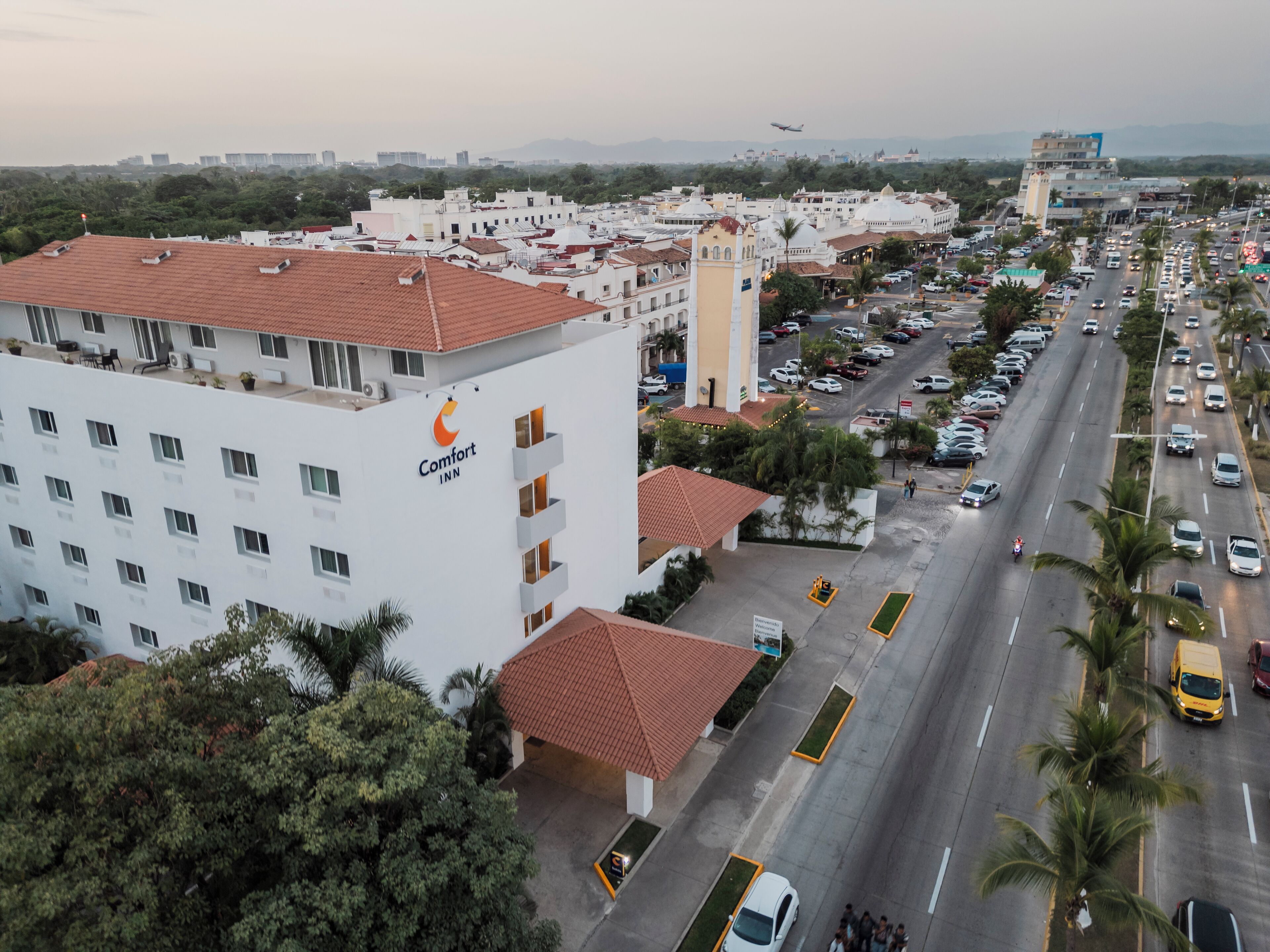 Un hotel Comfort Inn con tetto in tegole rosse, diversi piani e un parcheggio pieno di auto.