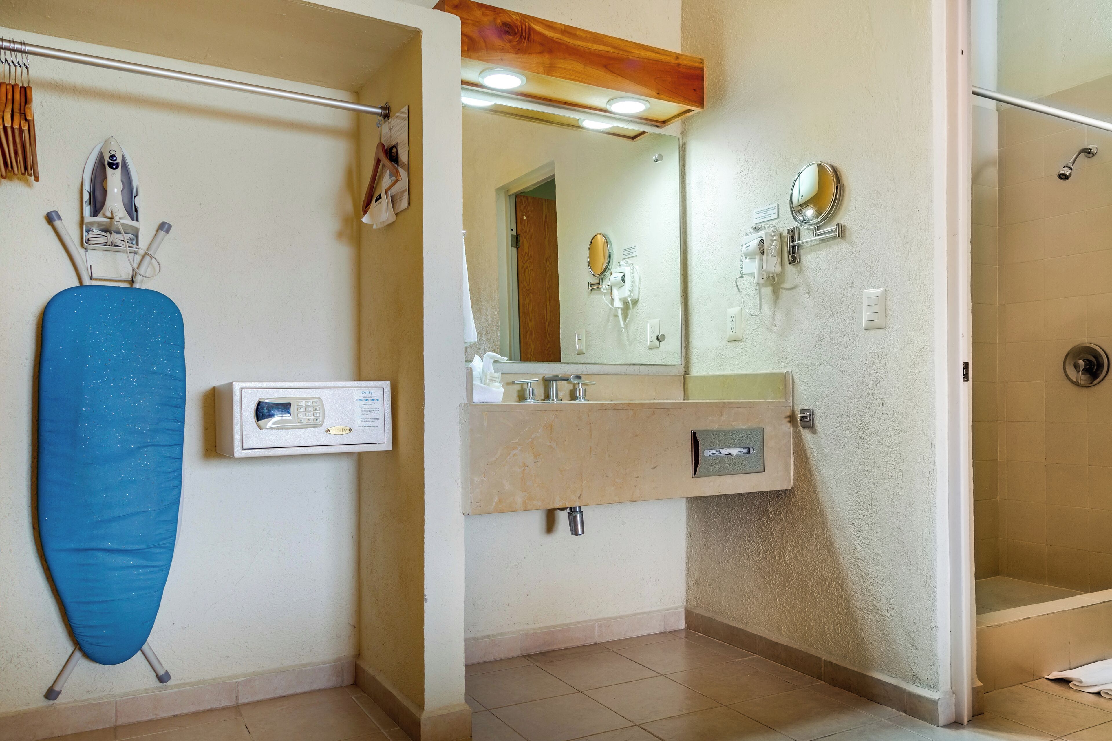 A bathroom with a shower, a sink with a mirror, and an ironing board.