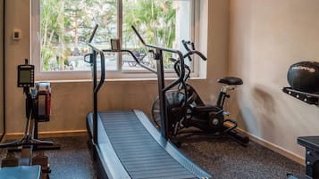 Een fitnessruimte met een loopband, hometrainer en roeimachine.