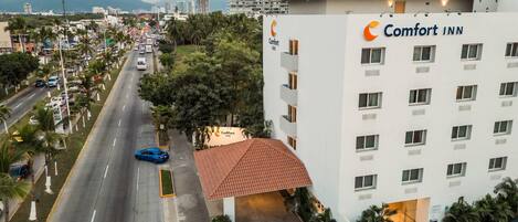 Een Comfort Inn hotel met uitzicht op een drukke straat en palmbomen.