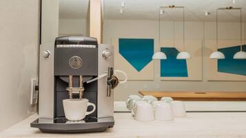 A modern coffee machine with a cup of coffee, a mirror, and a wall with geometric decor.