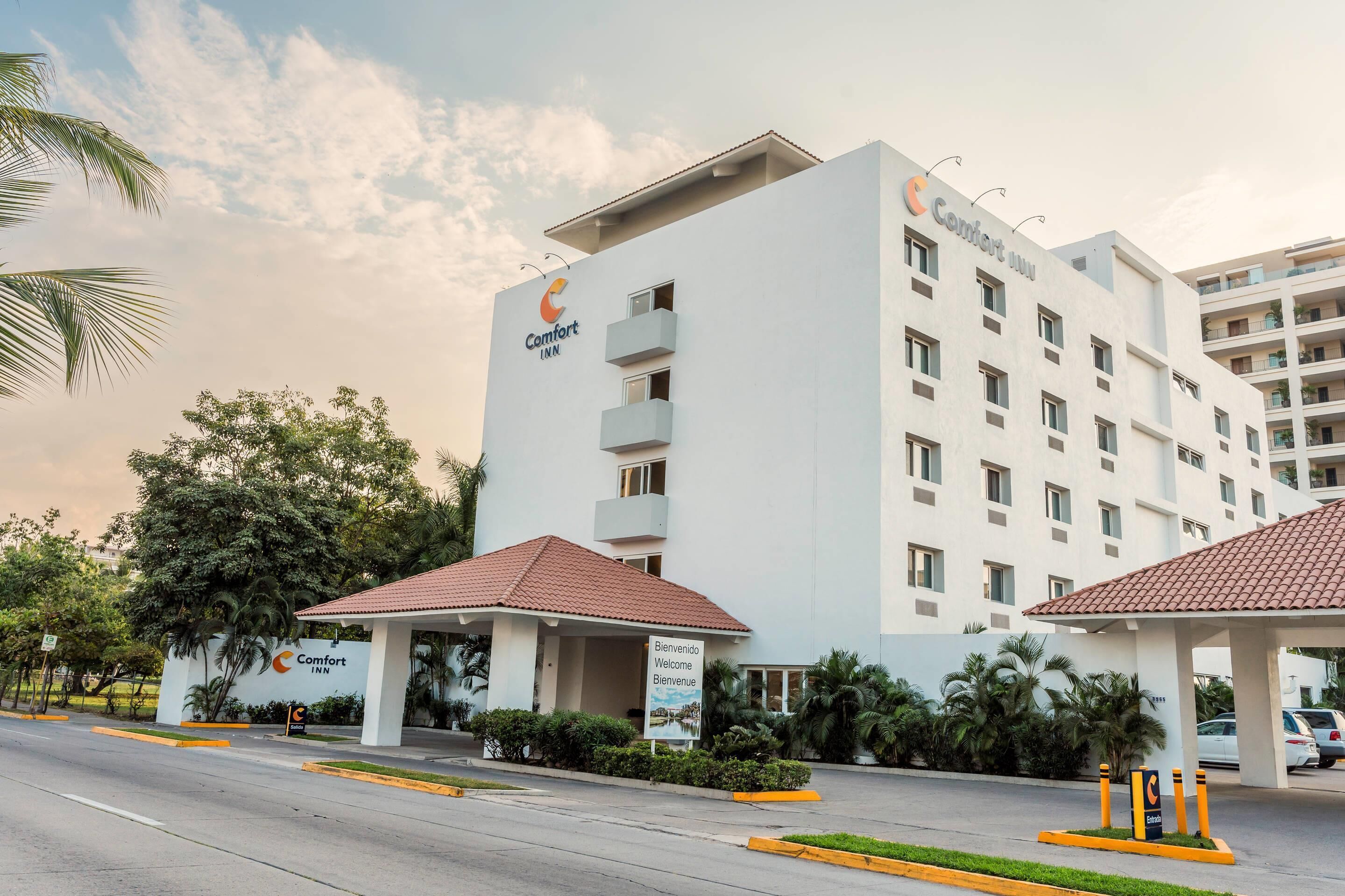 A multi-story hotel with a white facade and a red-tiled roof.