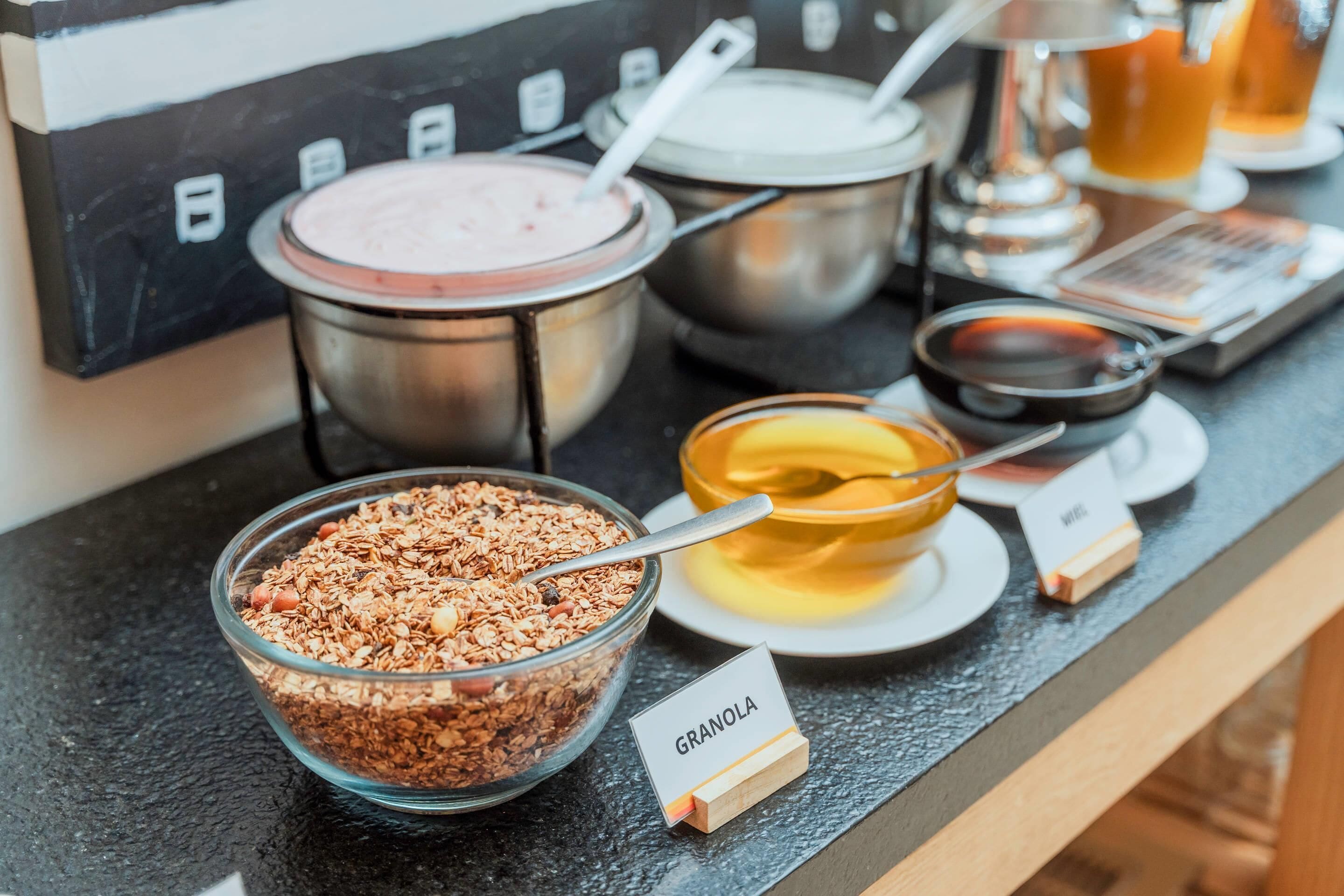 Un buffet proposant divers plats, notamment des céréales, du yaourt et un bol de soupe.