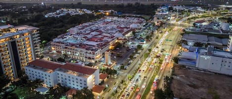 An aerial view of a hotel complex with multiple buildings, a parking area, and a busy road with vehicles.