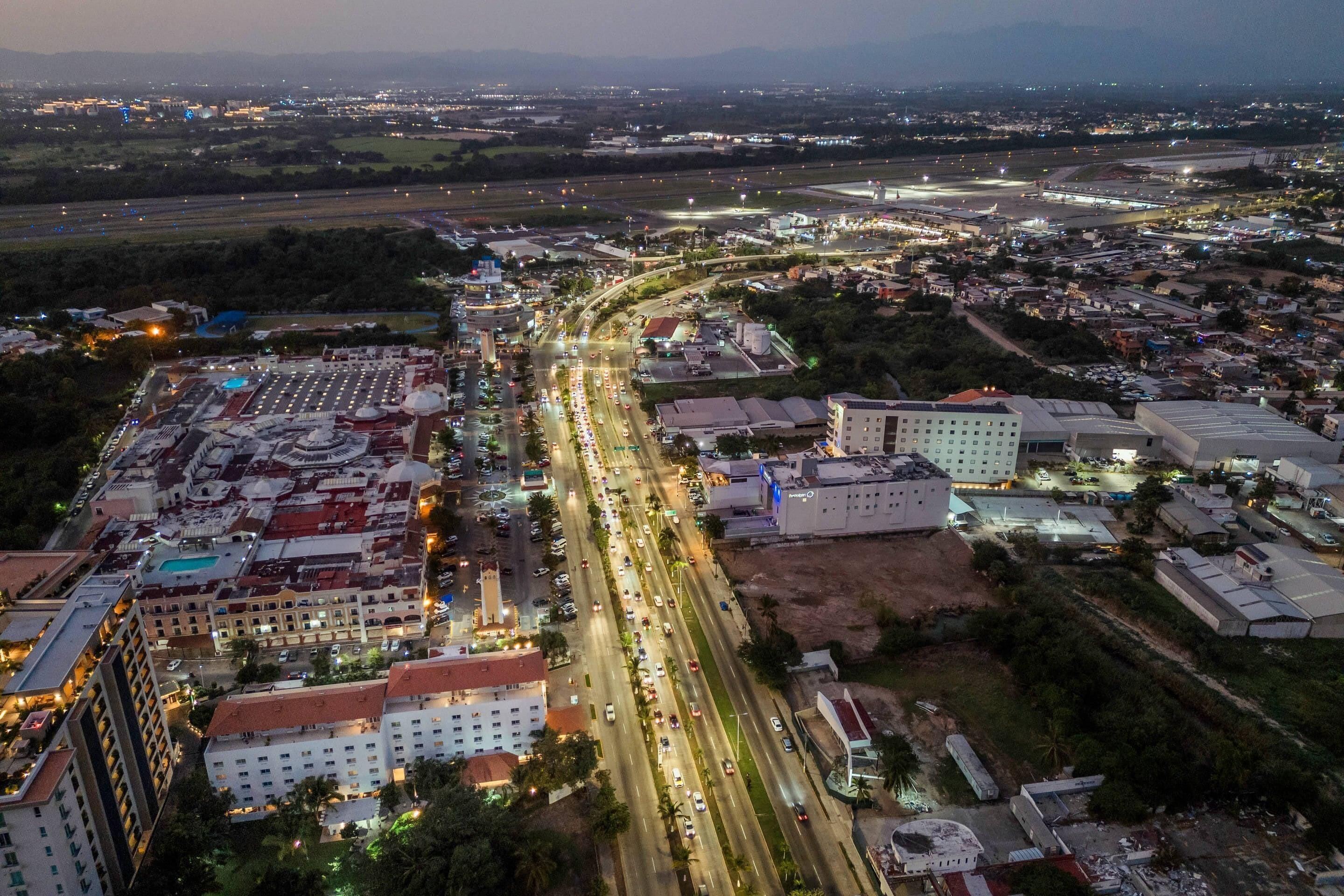 An aerial view of a cityscape with a prominent road, buildings, and a large dome structure.